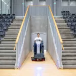 Advance SC4000 rider scrubber driving inbetween gymnasium stands.