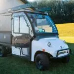 Columbia Utilitruck utility vehicle with cab parked on grass.