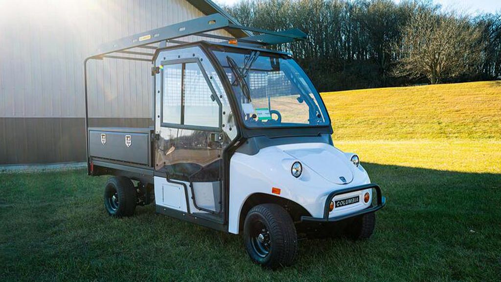 Columbia Utilitruck utility vehicle with cab parked on grass.