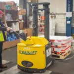 Combilift Combi-CS 4400 Pedestrian Stacker transporting pallet in warehouse, back view.