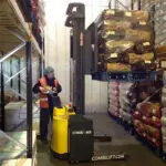 Combilift COMBI-WR Reach Stacker carrying a pallet off the shelf in a warehouse.