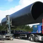 Combilift C55000 C-Series Forklift lifting giant tube onto truck trailer.