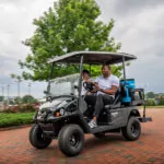 2 people driving in Cushman Shuttle 2+2 personnel carrier.