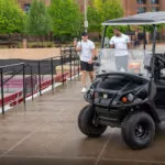 Tennis players walking to Cushman Shuttle 2+2 personnel carrier.