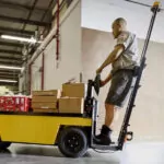 Employee driving Cushman Stock Chaser in a warehouse.