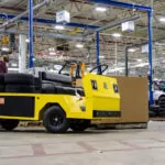 Cushman Titan XD burden carrier in manufacturing facility with tires loaded on cargo deck.