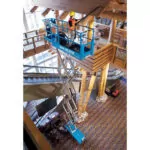 Genie GS-3232 scissor lift with operator raised in bucket.