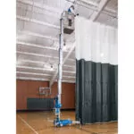 Repairman raised in Genie AWP-30S aerial work platform fixing dividing curtain in gymnasium.