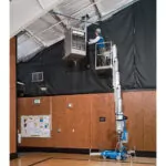 Technician raised in Genie AWP-30S aerial work platform repairing heater.