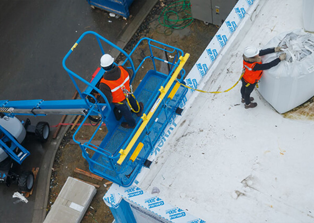 Operators working with Genie Boom lift with fall arrest bar accessory installed.