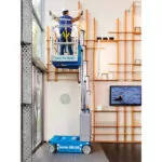 Worker repairing wall in Genie GR-20 vertical mast lift.