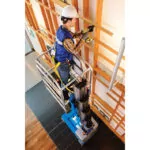 Construction worker repairing wall in raised bucket of Genie GR-20 aerial vertical mast lift.