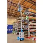 Worker raised to warehouse ceiling in Genie GR-20 vertical mast lift.
