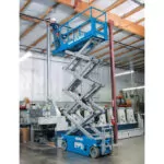 Genie GS-2362 slab scissor lift with employee in raised bucket.
