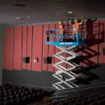 Workers raised in bucket of Genie GS-3232 scissor lift.