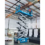 Repairman raised to ceiling in bucket of Genie GS-3246 scissor lift.