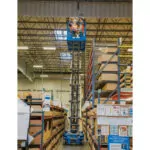 worker raised to warehouse ceiling in Genie GS-4046 scissor lift bucket.