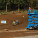 Operator driving across dirt bike trail in Genie GS-4390 scissor lift.
