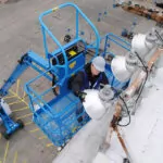 Man raised in boom lift bucket with Genie Operator Protective Structure (OPS) accessory.