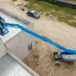 Genie S-40 HF and S-45 HF Telescopic Boom Lift raising workers to repair a building.
