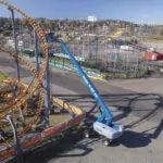 Genie S-65 XC aerial boom lift raising employees to work on rollercoaster.