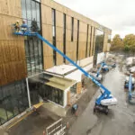 Genie S-65 XC telescopic boom lift lifting workers to repair the side of a building.