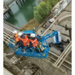 Workers in work bucket of Genie SX-125 XC boom lift.
