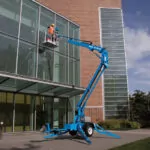 Worker raised and cleaning windows on Genie TZ-34/20 trailer-mounted boom lift.