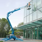 Workers cleaning building windows in Genie TZ-34/20 trailer-mounted boom lift.