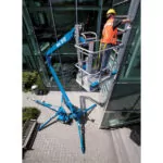 Worker raised in bucket of Genie TZ-50 trailer mounted boom lift.