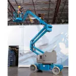 Genie boom lift raising employee to ceiling.