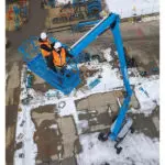 Two operators being raised in Genie ZX-135/70 articulating boom lift.