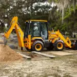 JCB 3CX Compact Backhoe Loader digging, side view.