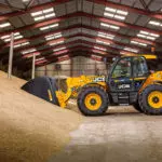 JCB 560-80 Agri Plus loadall scooping materials with bucket attachment.