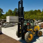 JCB 950 rough terrain forklift stacking materials at work site.
