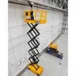 JCB S3246E electric scissor lift extended, with operator fixing a rail.