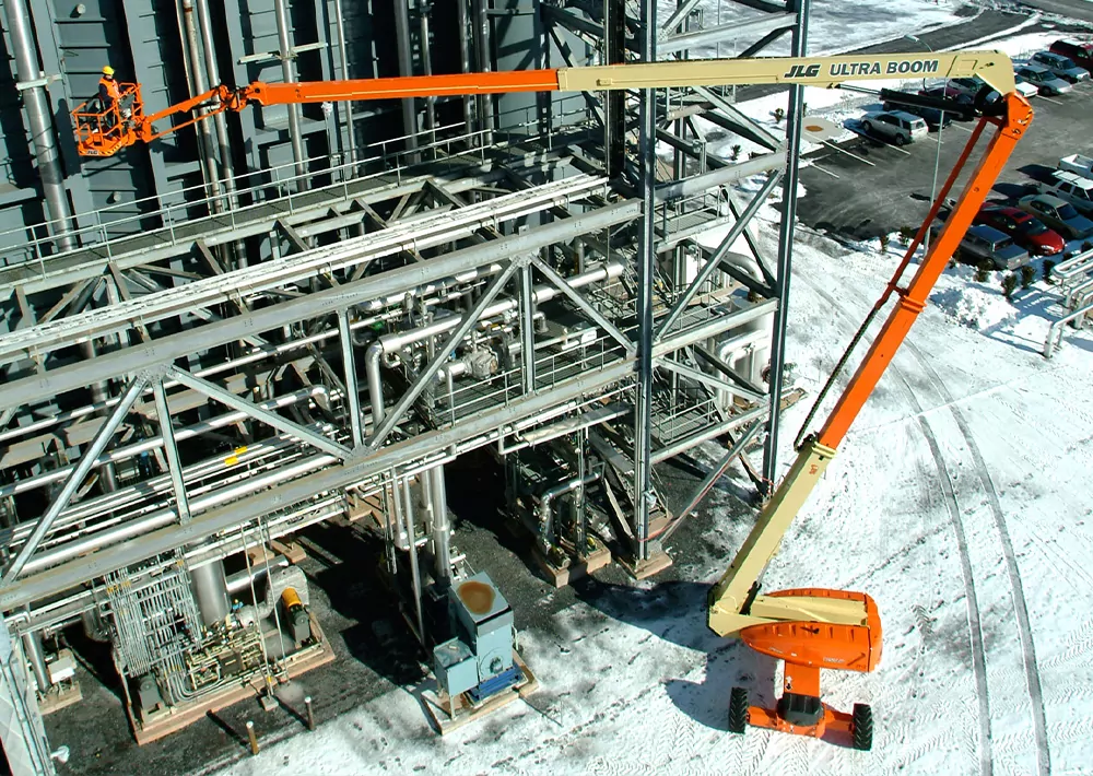 JLG Ultra Boom Lift raising worker over large metal rack structure.