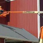 JLG 600AJ articulating boom lift raised against barn.