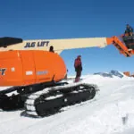 JLG 660SJC telescopic boom lift driving on snowy terrain.
