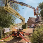 JLG X600AJ compact crawler boom lift on outdoor path.
