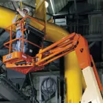Worker in bucket of JLG E300AJP boom lift.