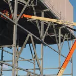 Worker in bucket of JLG Ultra Boom Lift inside building frame.