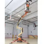 JLG X500AJ boom lift extended to garage ceiling.