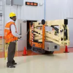 JLG X600AJ compact crawler boom lift lowered and going through doorway.