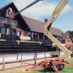 JLG X600AJ boom lift raising worker to provide building maintenance.