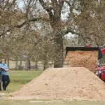 Mahindra 2638 compact utility tractor: bucket raised, dumping dirt into pile.