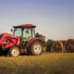 Mahindra 2670 tractor in field near hay bales.