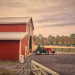 Mahindra 6075 tractor with cab driving out of farm.