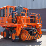 Rail King RK330 G6 mobile railcar mover in concrete lot outside a building.