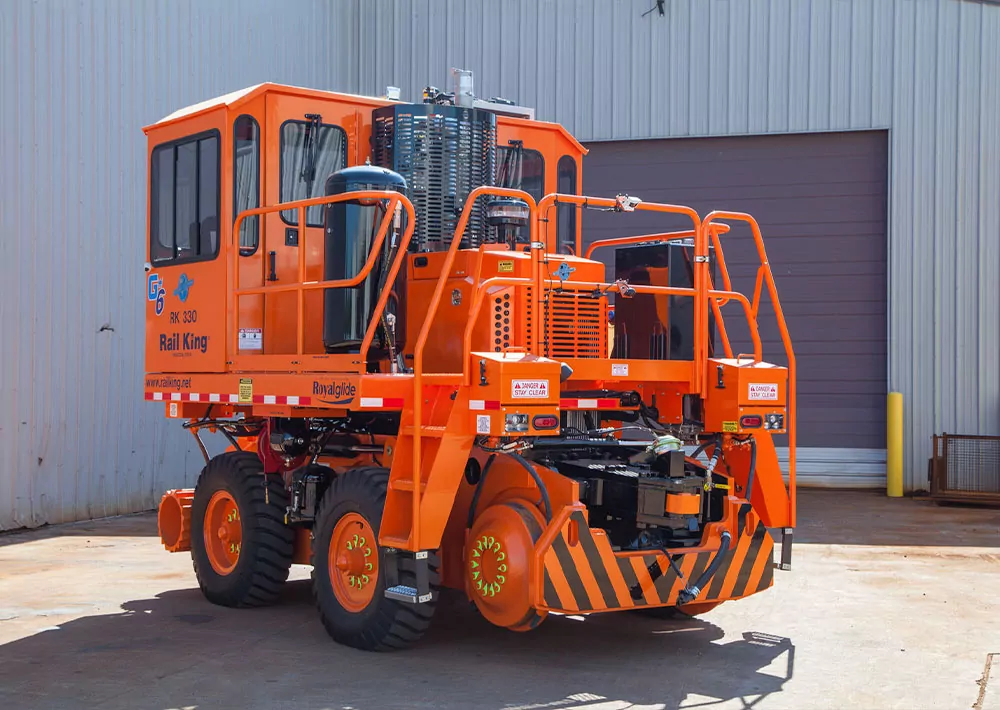 Rail King RK330 G6 mobile railcar mover in concrete lot outside a building.